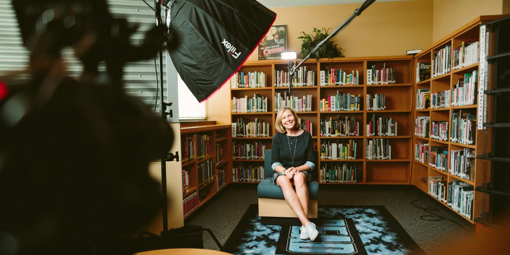 woman sitting on armless chair with light between bookcases in room