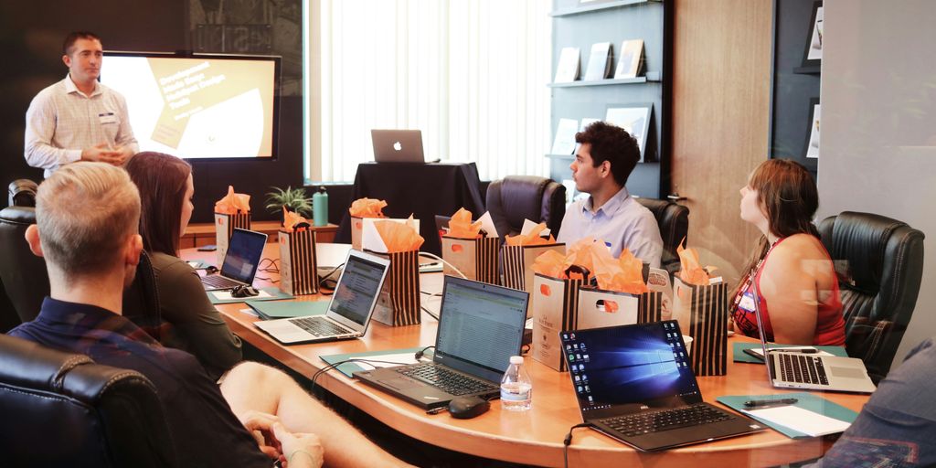 man standing in front of people sitting beside table with laptop computers