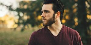 man wearing maroon V-neck t-shirt in forest