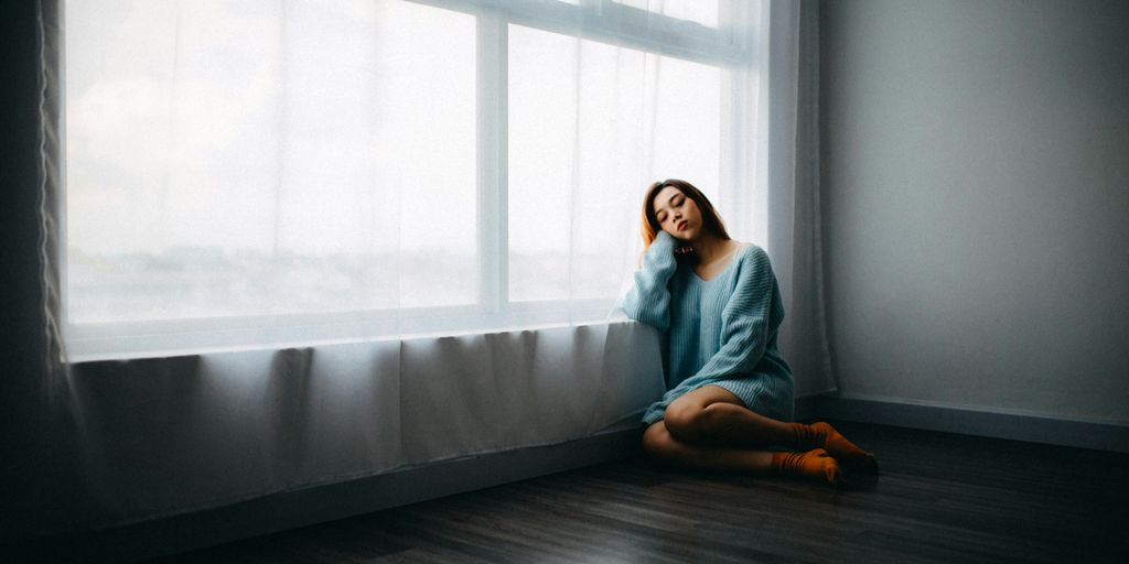 woman sitting on floor near window